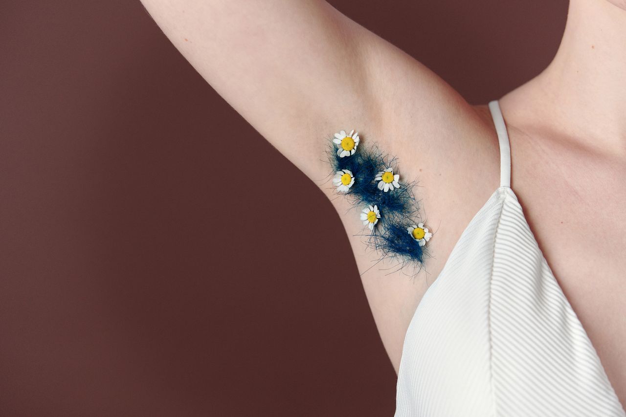 A unique artistic close-up of underarm hair decorated with daisies against a brown background.